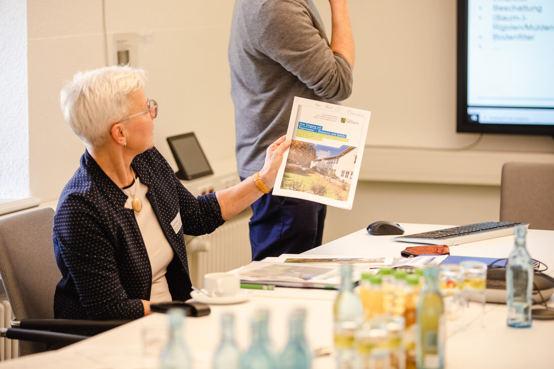 Steffi Förtsch moderiert den Workshop 2 und zeigt eine Broschüre zum dezentralen Hochwasserschutz 