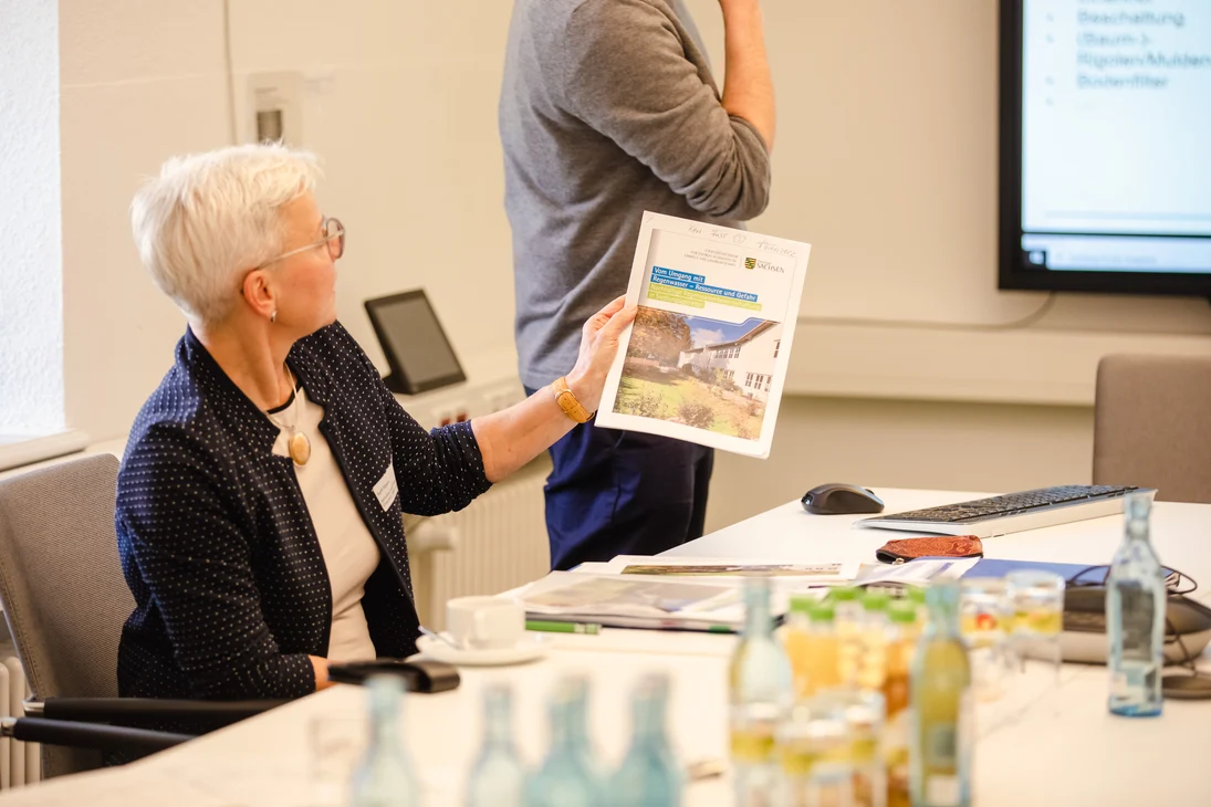 Steffi Förtsch moderiert den Workshop 2 und zeigt eine Broschüre zum dezentralen Hochwasserschutz