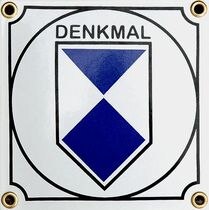 Zu sehen ist die Denkmalplakette, weiß und blau im kreis angeordnet. Drüber steht "Denkmal"