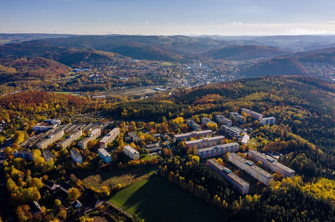 Der Brünlasberg im Erzgebirge: Luftaufnahme von langen Reihen von Plattenbauten unmitten von Wäldern.