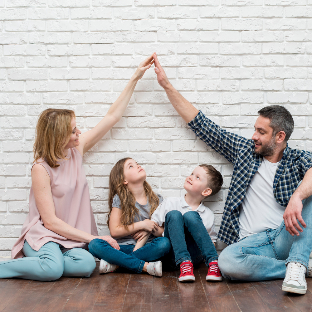 Familie hebt die Arme und bildet ein Dach über den Köpfen der zwei Kinder